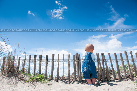 Toddler holding on to a picket fence on a beach. Стоковое фото, агентство Ingram Publishing / Фотобанк Лори