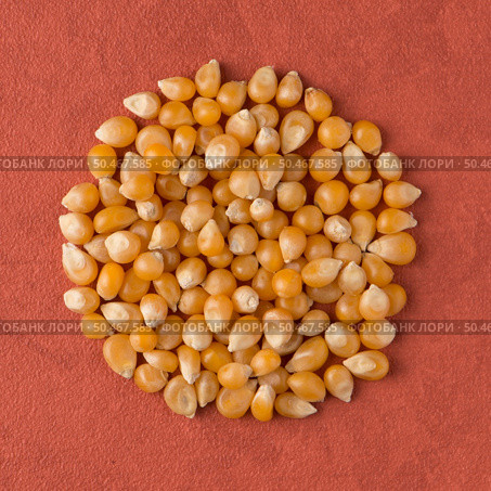 Top view of circle of corn against red vinyl background. Стоковое фото, агентство Ingram Publishing / Фотобанк Лори