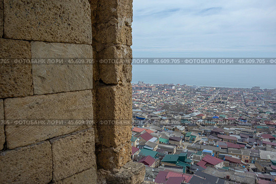 Top view of the ancient city from the loophole of the fortress. The Caspian Sea stretches beyond the houses of the city of Derbent. View of the old quarters of Derbent from the Naryn-Kala fortress. Стоковое фото, фотограф Эдуард Белкин / Фотобанк Лори