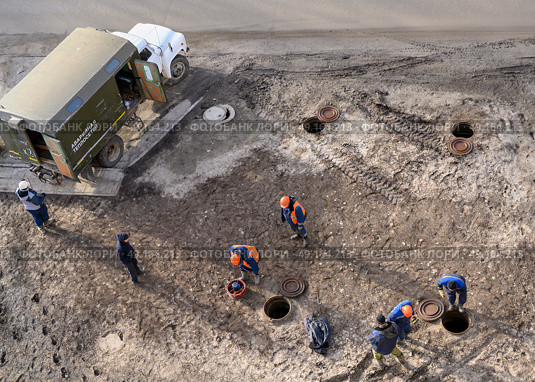 Top view of workers repairing underground heating mains through open hatches, the inscription on the truck: 'Emergency heating service' Стоковое фото, фотограф Сергей Фролов / Фотобанк Лори