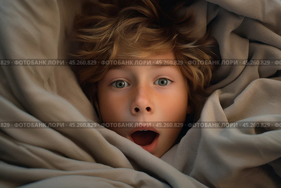 Top view, portrait of Boy with freckles lied in bed under blanket and yawns with wide opened mouth. He surprised, screaming or startled. Kid is surrounded by grey pillow and blanket. Стоковое AI-изображение, AI-художник Sergey Grishin / Фотобанк Лори