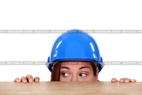 Tradeswoman peeping out from beneath a table. Стоковое фото, агентство Ingram Publishing / Фотобанк Лори