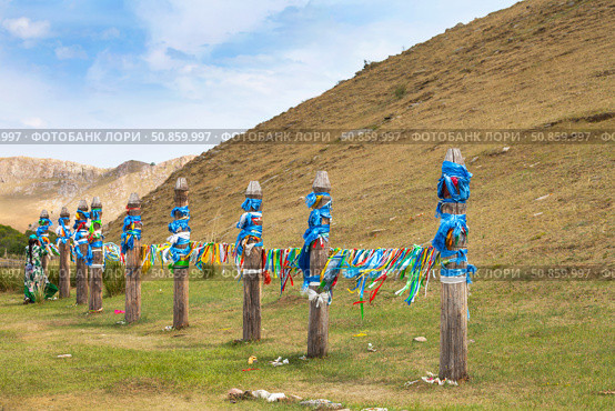 Traditional Buddhist pillars Serge with colored ribbons near sacred mountain Erd during Erdynskie Games festival on summer sunny day. Elantsy, Olkhon district, Siberia, Russia. Стоковое фото, фотограф Виктория Катьянова / Фотобанк Лори
