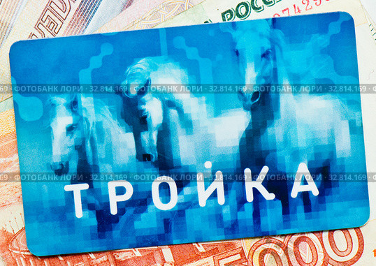 Транспортная карта «Тройка» на фоне денежных купюр (2020 год). Редакционное фото, фотограф E. O. / Фотобанк Лори