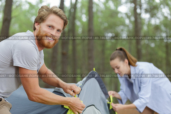 travelers assembling tent to spend night by the lake. Стоковое фото, агентство Ingram Publishing / Фотобанк Лори