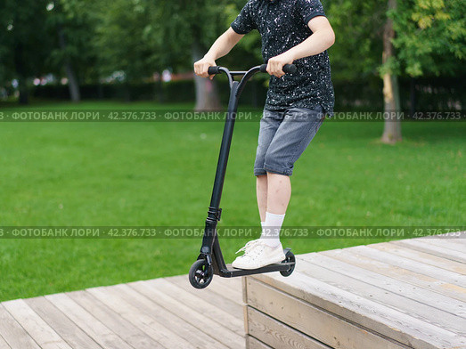 Trick at sportive push scooter in the park. Стоковое фото, фотограф YuryKara / Фотобанк Лори