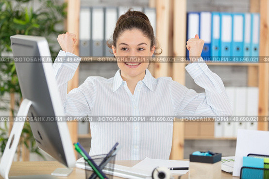 triumphant young secretary sat at computer desk. Стоковое фото, агентство Ingram Publishing / Фотобанк Лори