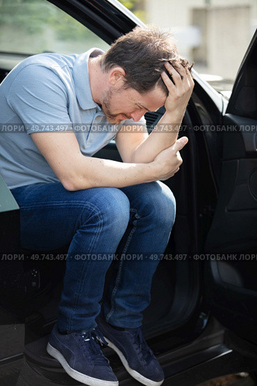 troubled man sat in his car with the door open. Стоковое фото, агентство Ingram Publishing / Фотобанк Лори