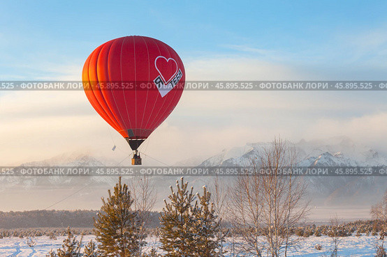 TUNKA VILLAGE, KYREN DISTRICT, BURYATIA, RUSSIA - January 04, 2025: People travel by hot air balloon over the snowy peaks of the Eastern Sayan Mountains during the winter holidays. Стоковое фото, фотограф Виктория Катьянова / Фотобанк Лори