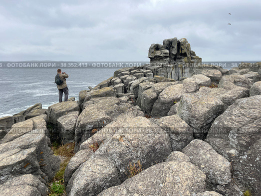 Турист фотографирует море с побережья полуострова Брюса осенью в дождливую погоду. Россия, Приморский край (2022 год). Редакционное фото, фотограф Овчинникова Ирина / Фотобанк Лори