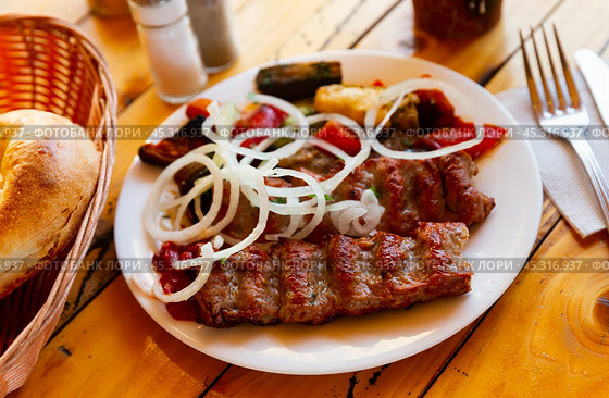 Turkish lula mutton kebab with onion and vegetables on table. Стоковое фото, фотограф Яков Филимонов / Фотобанк Лори