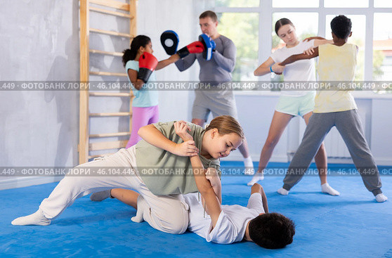 Tween girl practicing painful armlock in training bout with boy during self defence course. Стоковое фото, фотограф Яков Филимонов / Фотобанк Лори