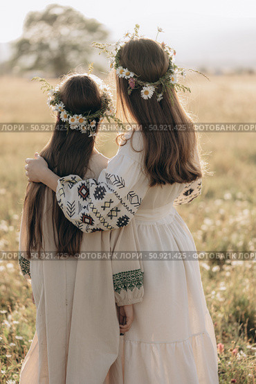 Two girls in folk dresses and flower wreaths in a field. Стоковое фото, фотограф София Тюленева / Фотобанк Лори
