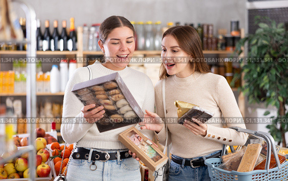 Two girls in store while shopping, choose sweets and chat sweetly. Стоковое фото, фотограф Яков Филимонов / Фотобанк Лори