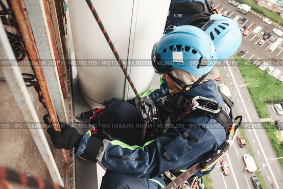 Two industrial mountaineering laborers in uniform and helmets hanging over residential building facade. Workers working on wall, access high rise work. Industry urban work concept. Copy ad text space. Стоковое фото, фотограф Aleksandr Golubev / Фотобанк Лори