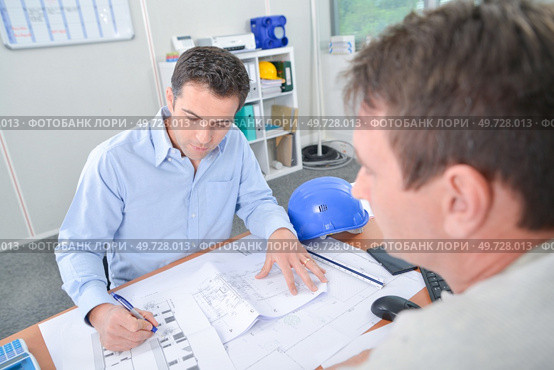 Two men at desk looking at blueprints. Стоковое фото, агентство Ingram Publishing / Фотобанк Лори