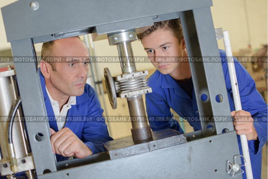 Two men looking at cylinder in vertical vice. Стоковое фото, агентство Ingram Publishing / Фотобанк Лори