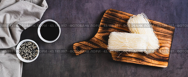 Two servings of funchose dry rice noodles on a board on the table top view web banner. Стоковое фото, фотограф Елена Руй / Фотобанк Лори