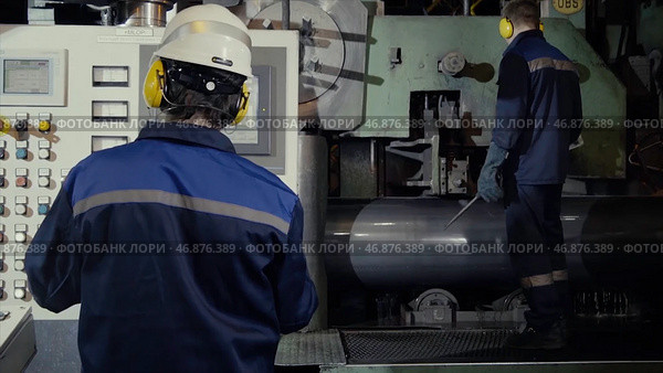 Two workers in production plant as team discussing, industrial scene in background. Стоковое фото, фотограф David Kashakhi / Фотобанк Лори