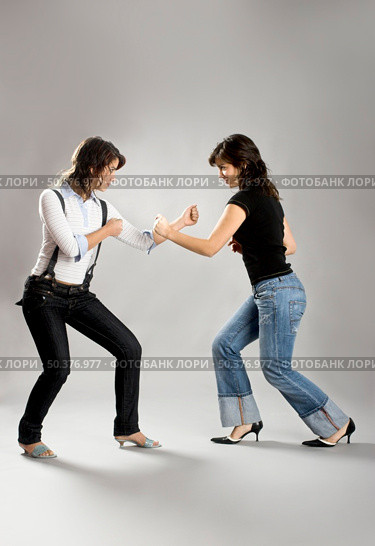 Two young beautiful sisters having fun simulating a fight  - This models are true twins. Стоковое фото, агентство Ingram Publishing / Фотобанк Лори