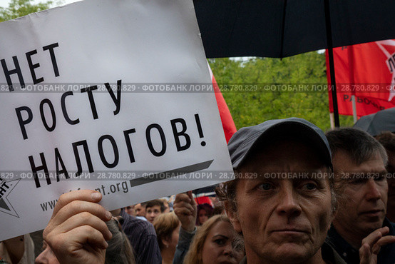 Участник митинга против повышения пенсионного возраста  и налогов держит плакат с надписью "Нет росту налогов" на территории Гайд-парка в парке Сокольники города Москвы, Россия (2018 год). Редакционное фото, фотограф Николай Винокуров / Фотобанк Лори