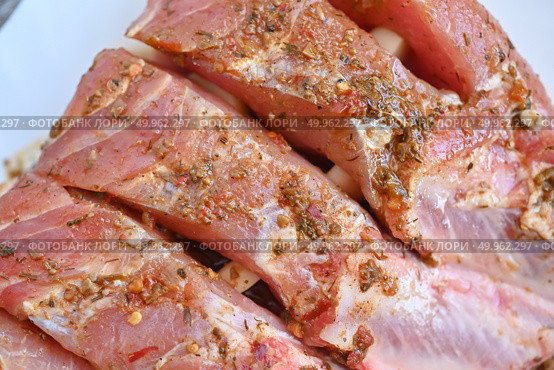 Uncooked seasoned pork ribs on a white cutting board. Isolated on white background. Стоковое фото, фотограф Светлана Акифьева / Фотобанк Лори