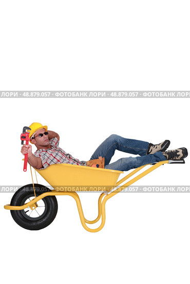 Unmotivated laborer resting in a wheelbarrow. Стоковое фото, агентство Ingram Publishing / Фотобанк Лори