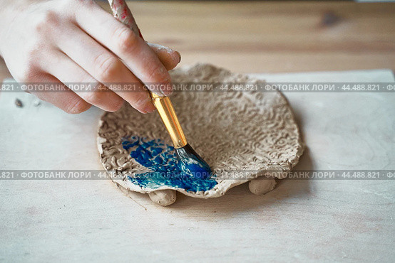Unrecognised Woman making pattern on ceramic plate, hands close-up. Стоковое фото, фотограф Natalia Gdovskaia / Фотобанк Лори