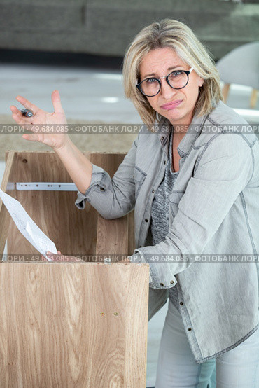 unsure woman is trying to fix a furniture. Стоковое фото, агентство Ingram Publishing / Фотобанк Лори