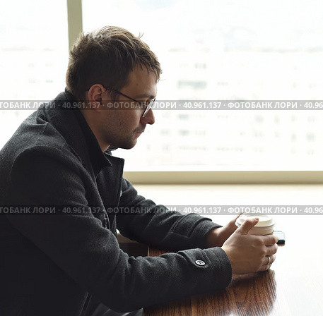 Upset depressive russian man looking thoughtfully to the side. paper cup of coffee in hands. sadness and despair concept. Стоковое фото, фотограф Татьяна Терехина / Фотобанк Лори