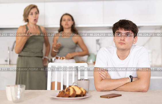 Upset guy dont speaking after discord with mother and wife standing behind. Стоковое фото, фотограф Яков Филимонов / Фотобанк Лори