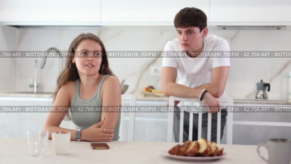 Upset young woman sitting at the kitchen-table with her back to her husband disputing with her. Стоковое видео, видеограф Яков Филимонов / Фотобанк Лори