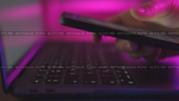 Use of mobile phone in trendy neon lights with laptop. Creative vivid color of ultraviolet red and blue. Hands of Girl scrolling up photos Close-up at dark room. App for sale in shop, Social media. Стоковое видео, видеограф Марина Демидюк / Фотобанк Лори