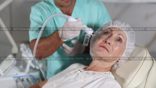 Using cosmetic workstation, male physician enhances the woman's features through tailored procedures. Стоковое видео, видеограф Яков Филимонов / Фотобанк Лори