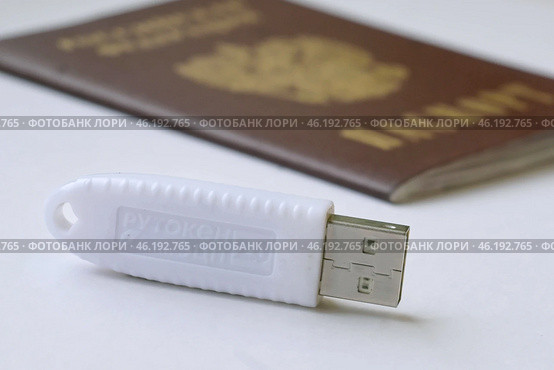 Устройство  USB eToken  (рутокен) белого цвета, устройство для хранения электронной цифровой подписи (ЭЦП) и информации для аутентификации пользователя и паспорт на белом фоне. Редакционное фото, фотограф Snezka / Фотобанк Лори