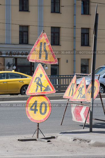 Ведутся дорожные работы. На проезжей части стоят дорожные знаки "Сужение дороги справа", "Дорожные работы", "Ограничение скорости" (2019 год). Стоковое фото, фотограф Наталья Николаева / Фотобанк Лори