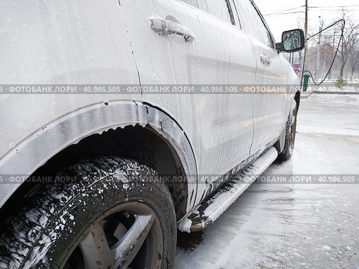 Very dirty white SUV, doused with shampoo and foam, stands in the  box of outdoor self-service car wash and waits for washing. Очень грязный белый внедорожник, облитый шампунем и пеной, стоит в боксе уличной автомойки самообслуживания и ждет мойки. Стоковое фото, фотограф Дмитрий Березнев / Фотобанк Лори