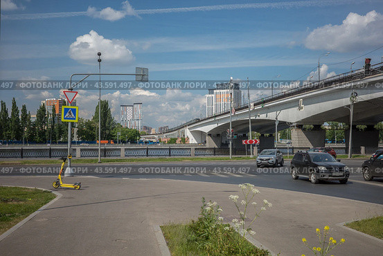 Весенний пейзаж с Москва-рекой, Нагатинским метромостом, самокатом и цветамии. Москва, Нагатино-Садовники, май 2024г. Редакционное фото, фотограф Казума / Фотобанк Лори