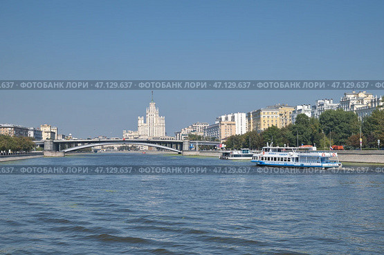 Вид на Большой Краснохолмский мост и высотное здание на Котельнической набережной в Москве, Россия. Прогулочный теплоход плывет по Москве-реке (2024 год). Редакционное фото, фотограф Елена Коромыслова / Фотобанк Лори