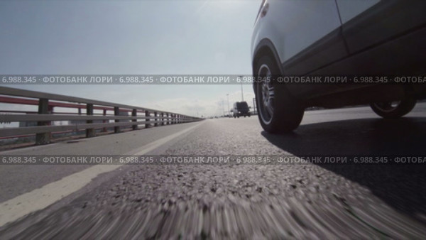 Вид на дорогу и проносящуюся дорожную разметку с переднего колеса автомобиля. Стоковое видео, видеограф Кекяляйнен Андрей / Фотобанк Лори