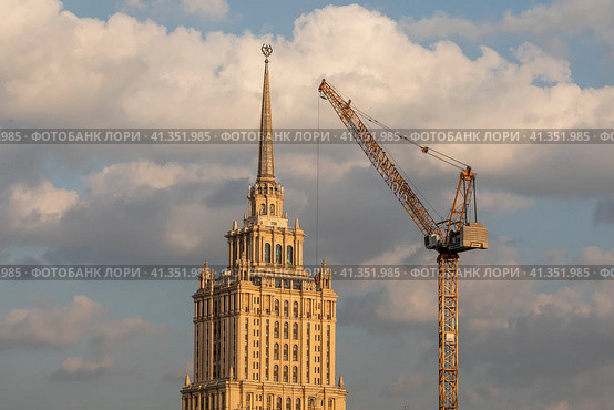 Вид на шпиль отеля "Рэдиссон Ройал, Москва" (гостиница "Украина") на фоне строительных башенных кранов в центре города Москвы, Россия (2023 год). Редакционное фото, фотограф Николай Винокуров / Фотобанк Лори