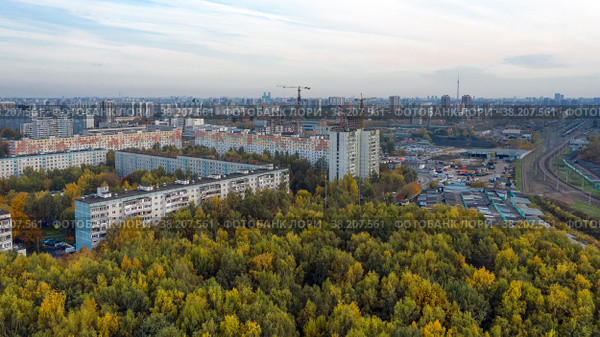 Вид с воздуха на жилые дома в московском районе Лианозово и Бескудниково со стороны Линозовского парка летним вечером на закате. Железнодорожная линия разделяет районы города (2021 год). Стоковое фото, фотограф Pukhov K / Фотобанк Лори