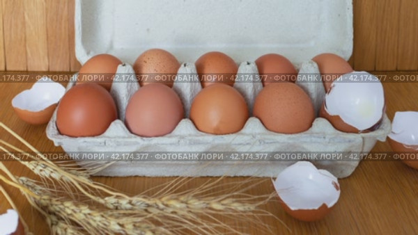 Video of chicken eggs in environmental packaging made of cardboard, egg shells and dry wheat ears on wooden table. Dietary organic healthy food. Стоковое видео, видеограф Виктория Катьянова / Фотобанк Лори