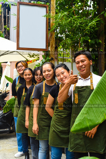 Vietnamese coffee shop team smiling and standing together against a cafe. Стоковое фото, фотограф Татьяна Терехина / Фотобанк Лори