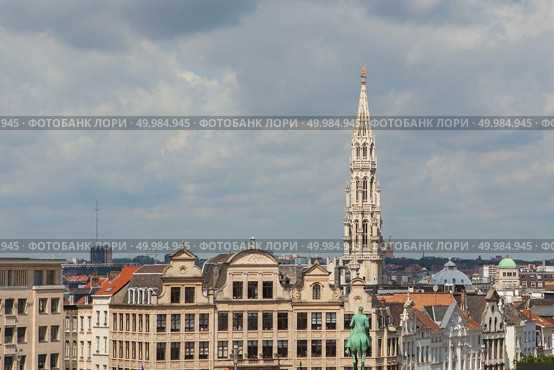 View from a distance the spire of the City hall of Brussels on Grand place square, dark storm clouds hovering over the majestic buildings and the roofs of neighboring houses, Brussels, Belgium. View from a distance the spire of the City hall. Стоковое фото, агентство Ingram Publishing / Фотобанк Лори