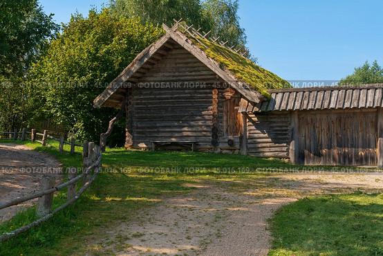 View of an ancient log outbuilding on the territory of the Pushkin village in Bugrovo of the Pushkin Museum-Reserve on a sunny summer day, Pushkinskiye Gory, Pskov region, Russia. Редакционное фото, фотограф Ula Ulachka / Фотобанк Лори