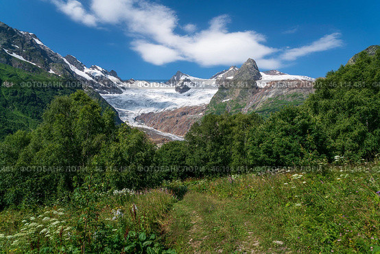 View of the Alibek glacier in the mountains of the North Caucasus on the territory of the Teberdinsky Nature Reserve on a sunny summer day, Dombay, Karachay-Cherkessia, Russia. Стоковое фото, фотограф Ula Ulachka / Фотобанк Лори