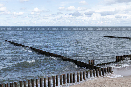 View of wooden breakwaters extending into the ocean, with gentle waves. Стоковое фото, фотограф EugeneSergeev / Фотобанк Лори