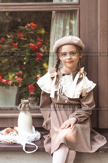 Vintage accessories and retro-style clothes. A small, beautiful girl with bows in her hair, in a beige dress and a beret outdoors with bagels and milk in a string bag. Стоковое фото, фотограф Photojuli / Фотобанк Лори