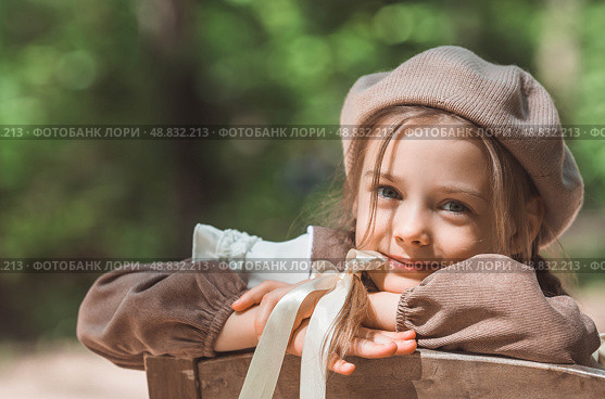 Vintage women's accessories and retro-style clothing. A small, beautiful girl with bows in her hair, in a beige dress and a beret outdoors. Стоковое фото, фотограф Photojuli / Фотобанк Лори